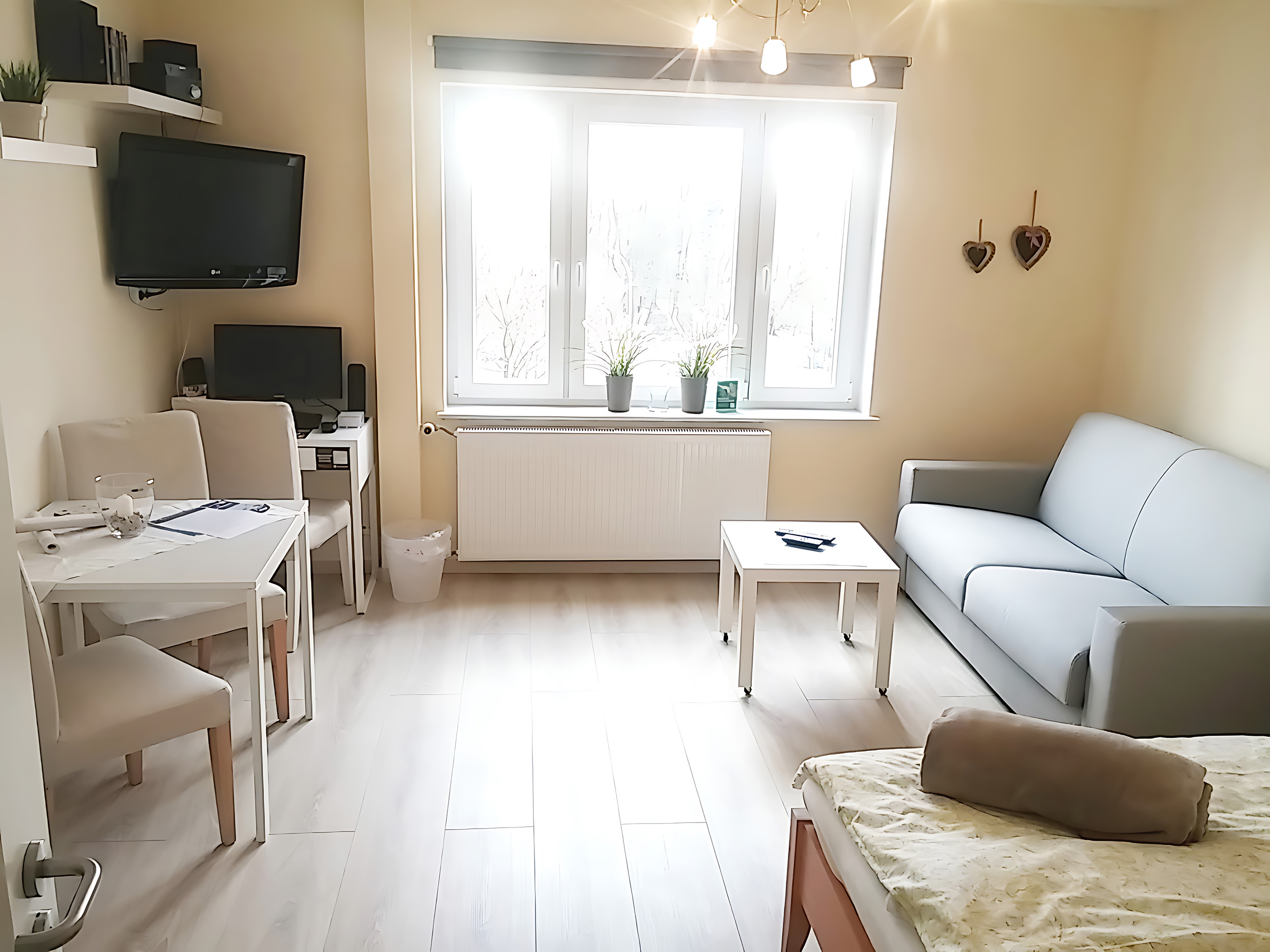 Wohnen auf Zeit – Helles Wohnzimmer – Modernes Wohnstudio mit Esstisch, Sofa, großem Fenster, TV-Bereich und freundlicher Einrichtung